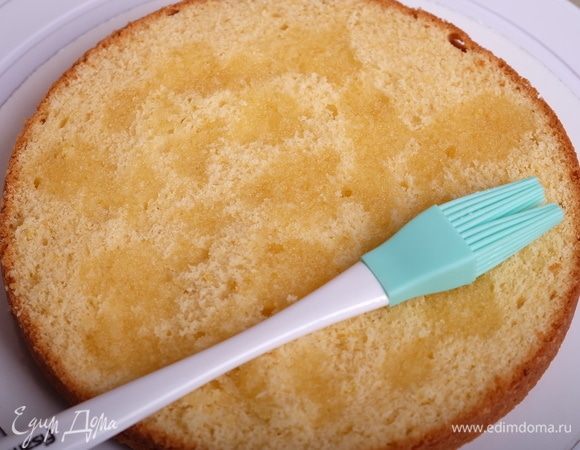 На подложку кладем первый корж и смазываем его силиконовой кисточкой небольшим количеством сиропа.