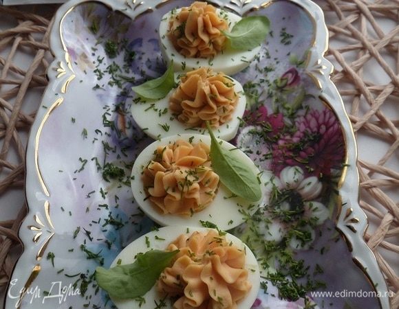 Выкладываем фаршированные яйца на блюдо. Посыпаем нарезанной зеленью.