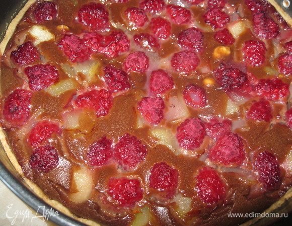 Духовку разогреть до 180°С. Тесто достать из холодильника, положить на него бумагу с грузом в виде гречки или фасоли и пропечь 15-20 мин. Затем бумагу снять, влить готовый крем, в него выложить груши и малину, как бы немного стараясь утопить их. Отправить в духовку еще на 30 мин. 