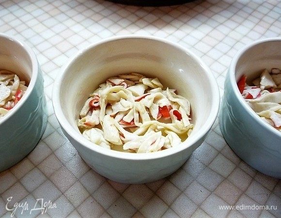 Керамические порционные формочки смазываем растопленным сливочным маслом, выкладываем крабовое мясо.