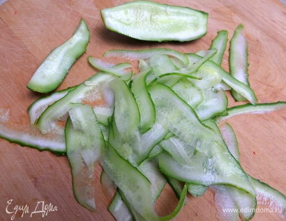 Огурец нарезать овощечисткой на слайсы.