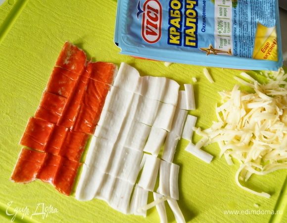 Крабовые палочки освободить от упаковки и развернуть, нарезать полосками. Сыр натереть на крупной терке.
