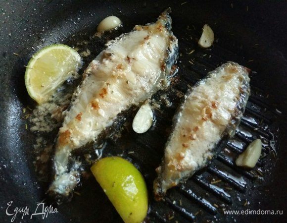 Перевернуть рыбку и выложить в сковороду чеснок, дольки лайма, посыпать розмарином и травками (щепотку), чтобы слегка оттенить вкус рыбы пряностью. Кому не нравится вкус пряных трав, можно и без трав обойтись легко. И жарим еще минут 5.