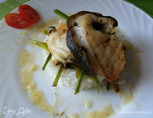 Рис выложить в кольцо, немного уплотнить, аккуратно убрать кольцо. Украсить луком-пореем, сверху 2 кусочка филе зубатки, полить вокруг соусом.