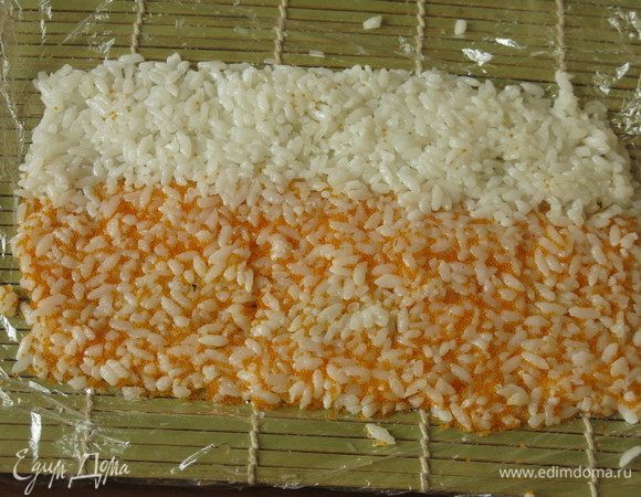 На пленку выкладываем рис цветной и белый, плотно прижимаем его, формируем коврик.