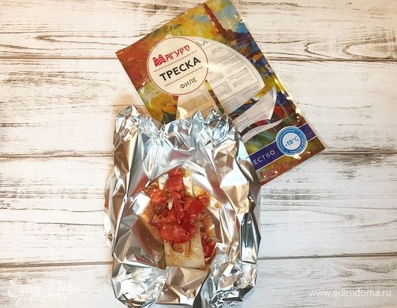 Рыбу предварительно разморозить. Из фольги сделать кармашек, положить один кусочек рыбы, сверху уложить заправку с помидорами и обязательно полить соком.