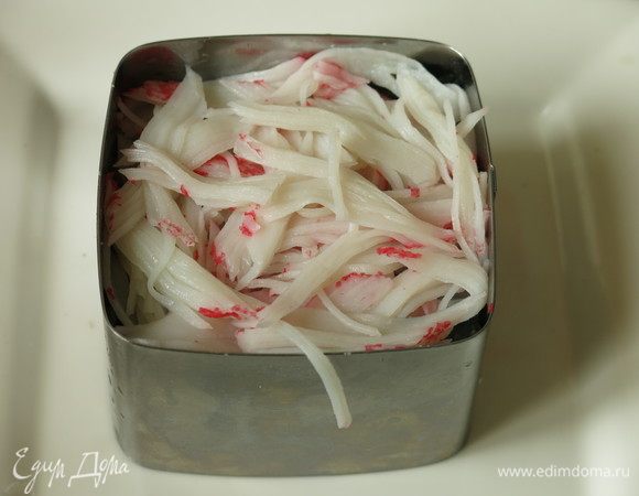 На нори нарываем крабовые палочки, в серии «Снежный краб» они укороченные, в пачке 150 г, 8 половинок. На этот слой пошло две штучки. Этот слой кладем свободно, плотно не прижимаем. Сбрызгиваем соусом соевым.