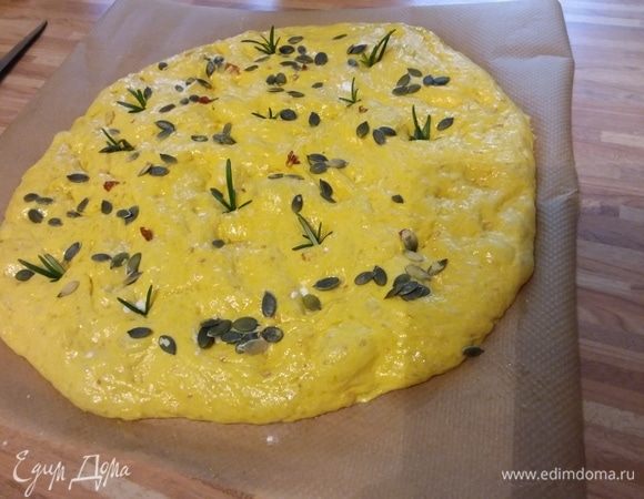 Подготовить лист пергаментной бумаги. С помощью лопаточки дать тесту сползти из миски на поверхность. Аккуратно пальчиками (пальцы предварительно окунуть в муку, чтобы они не прилипали к тесту) растянуть тесто, чтобы получить фокаччу овальной формы. Следить за тем, чтобы не повредить пузырьки воздуха.