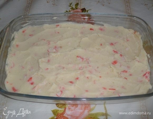 В подготовленную форму выкладываем картофельно-крабовую массу. Равномерно распределяем.