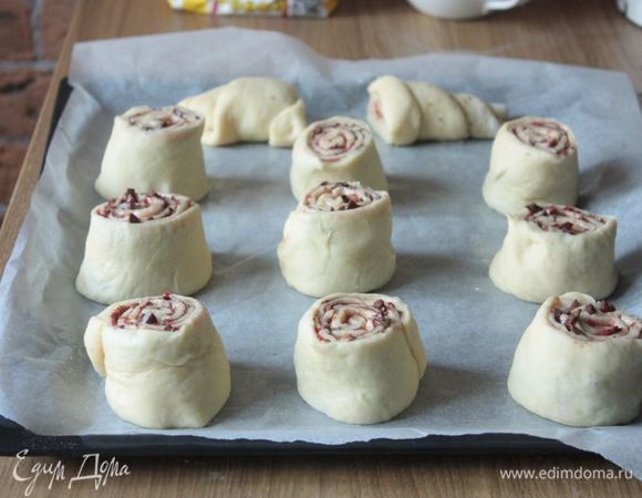 Рулет разрежьте на порционные булочки и выложите их на пекарскую бумагу или противень, обязательно смазанные сливочным маслом. Расстояние между ними должно быть приличным: они увеличатся в объеме минимум вдвое. Накройте будущие улитки полотенцем и оставьте на расстойку на 20–25 минут.