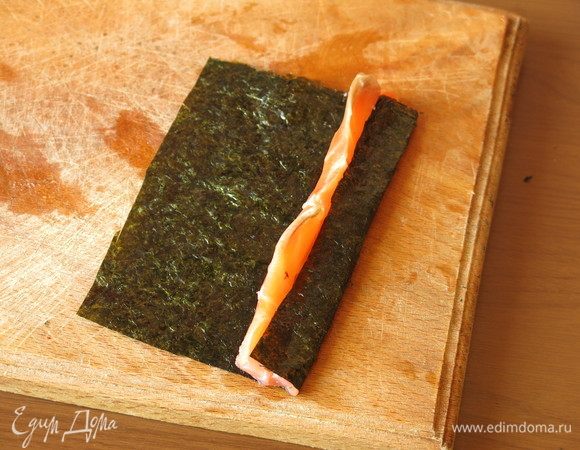 Оборачиваем семгу нори — начинаем с разреза, вкладываем край нори в половинку разреза.
