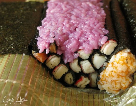 Сверху накладываем рис.  У меня он немного влажноват от сока, для удобства в работе его можно чуть подсушить салфеткой. Рис должен заполнить зубчики красной рыбы в нори и изгиб тела будущей рыбки.