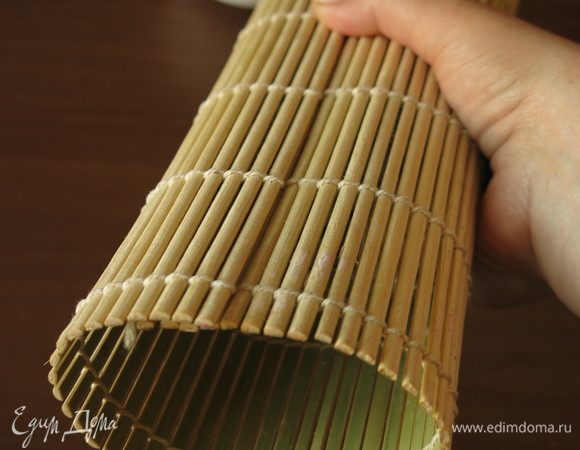 Прижимаем суши ковриком не меняя расположения, снизу придерживаем ладонью.