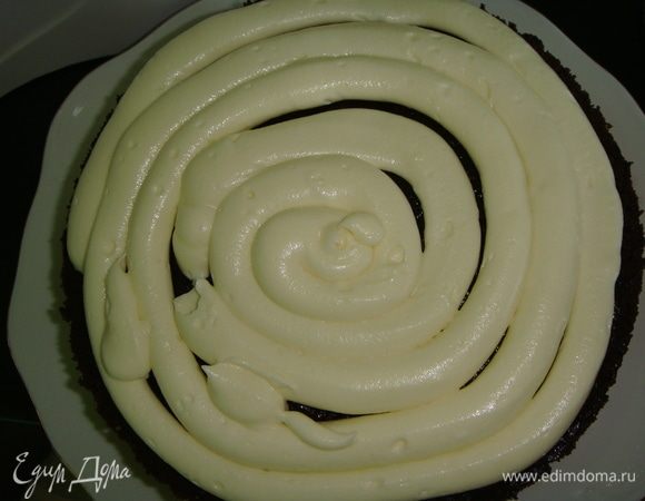 Приступаем к сборке торта. Коржи обрезать по тарелке, чтобы они были одного диаметра и ровные. Крем переложить в одноразовый кондитерский мешок и отрезать уголок диаметром 8 мм. На середину блюда выдавить немного крема положить шоколадный корж. Выдавливаем крем спиралью на корж.