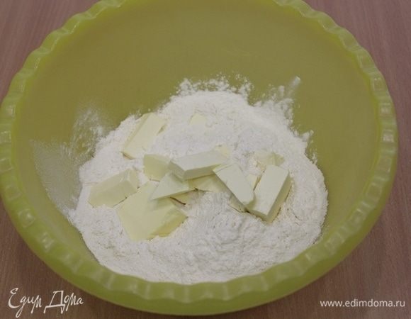 В миску просеять муку и перемешать ее с сахаром и солью, добавить холодное масло, перемешать быстро руками до состояния крошки.