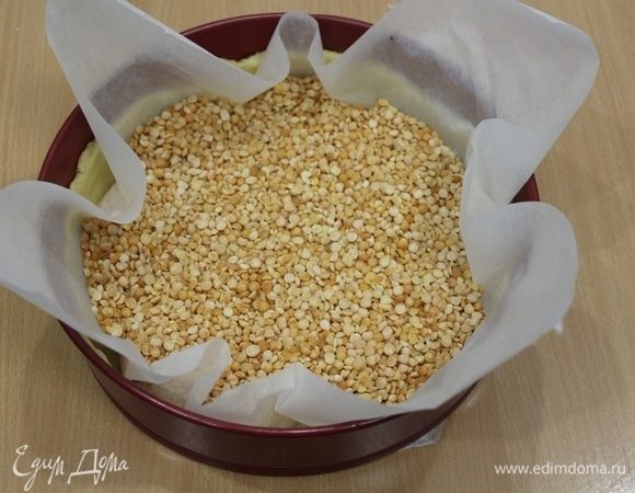 Нагрейте духовку до 170–180°C. Достать тесто из холодильника, застелить бумагой для выпечки, насыпать горох или фасоль. Отправляем тесто запекаться. Через 15 минут уберите груз и оставьте тесто еще на 10–15 минут, до легкой румяности дна.