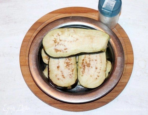 Укладываем пластины баклажана в миску и пересыпаем солью. Ставим миску с баклажаном в сторону до выделения капелек сока. Затем баклажан промываем холодной водой и кладем на бумажное полотенце, чтобы убрать излишки воды.