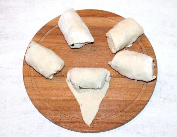 Раскладываем начинку на край, каждой части теста и сворачиваем в рулет. Получается пирожок-рогалик.