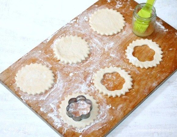 Приготовим волованы. На припыленную мукой разделочную доску кладем пластину теста. Не раскатывая тесто, вырезаем заготовки для волованов — это донышко и кольцо.
