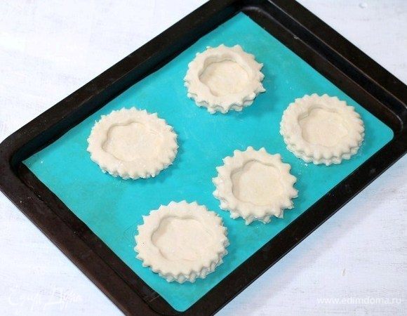 Перекладываем заготовки на противень, застеленный заранее силиконовым ковриком. Отправляем противень в духовку. Включаем минимальную температуру духовки от 40–100°C и оставляем волованы до увеличения в 2 раза.