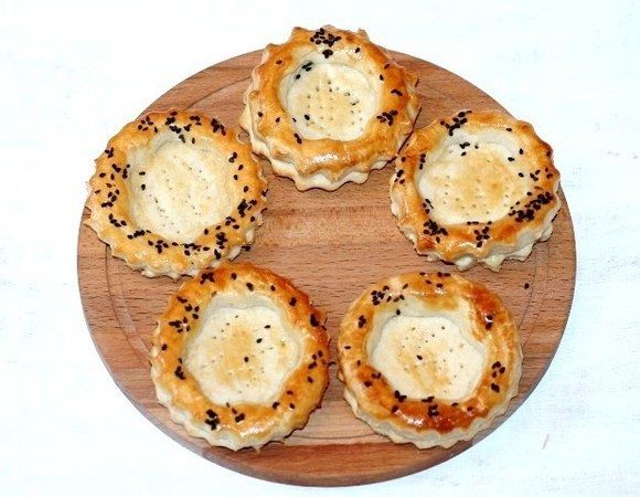 Затем смазываем волованы взбитым яйцом и посыпаем кунжутом. Переключаем духовку на 190°C и выпекаем волованы до золотистой корочки, минут 20. Ориентируйтесь на свою духовку. Испеченные волованы смазываем топленым сливочным маслом и накрываем сухим полотенцем. Оставляем до полного остывания.