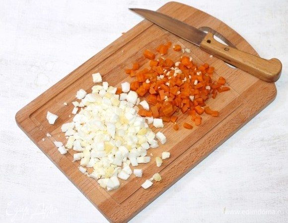 Очищенные и охлажденные морковь (небольшая) и вареные куриные яйца (2 шт.) нарезаем мелкими кубиками. Измельчаем очищенный зубчик чеснока и перемешиваем с морковью.
