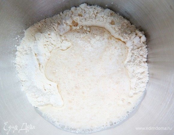 Делаем в центре мучной горки углубление и выливаем дрожжевую жидкость.
