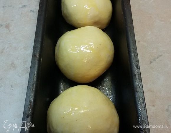 Форму для выпечки смазать горчичным маслом. Тесто разделить на три части. Из каждой части сформировать шарик и обильно со всех сторон кисточкой обмазать горчичным маслом. У меня три шарика. Оставить еще раз подняться на 1 час.