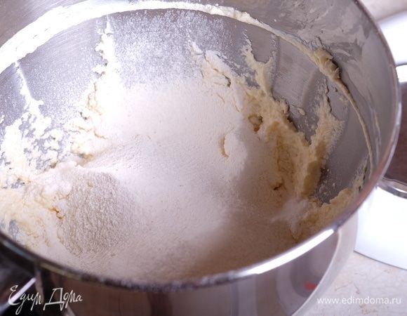 Смешать муку с разрыхлителем и солью, просеять в масляно-творожную смесь.