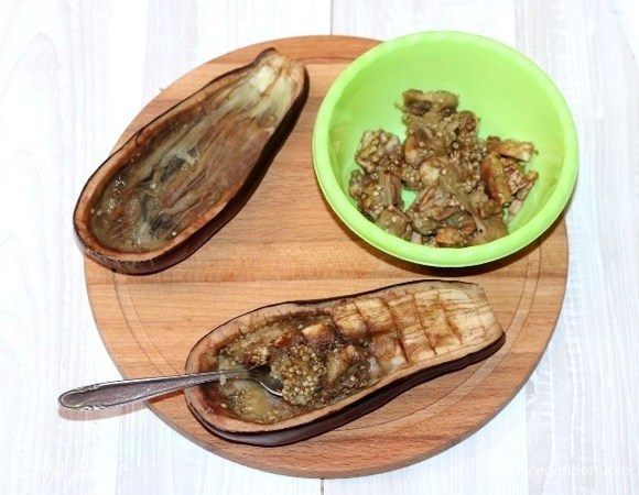 У немного остывшего баклажана удаляем аккуратно мякоть, чтобы не повредить шкурку. Мякоть баклажана кладем в миску.