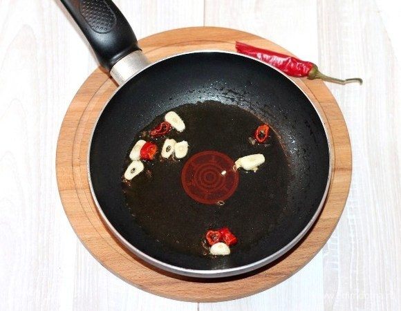 На разогретом растительном масле (2 ст. л.) обжариваем кусочки острого перца и порезанный слайдами чеснок до появления аромата. Овощи со сковороды удаляем, масло оставляем.