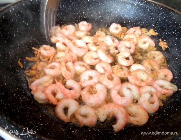 Высыпать креветки к чесноку.