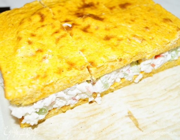 На 1 часть выложим салат и накроем сверху второй частью коржа.