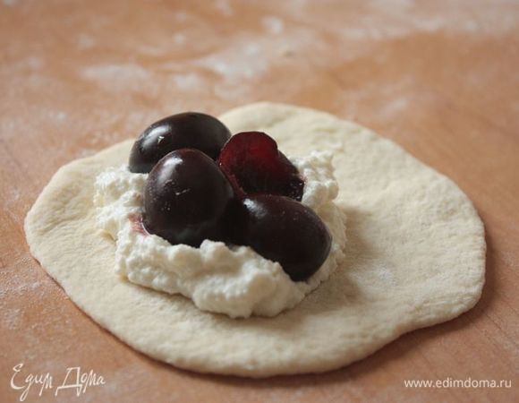 И начинаем лепить пирожки!
Для начинки взбейте творог с яйцами и сахаром. Из свежей вишни удалите косточки. 
Раскатайте каждый кусочек теста, выложите по 2 ч. л. творога и по 2-3 вишни. У меня была очень сладкая вишня, поэтому я не посыпала вишню сахаром, но знаю кучу людей, которые все же так делают. Поэтому, если хотите, можете посыпать вишню половинкой чайной ложки сахара.