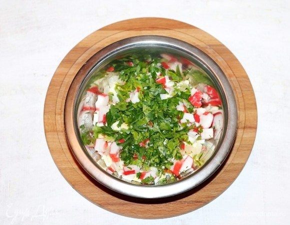 Приготовим начинку для блинов. В миску выкладываем: крабовые палочки, 1/2 часть репчатого лука, вареные яйца и 1/2 часть порубленной петрушки. Солим, перчим и перемешиваем. Начинка готова!
