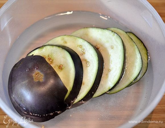 Баклажаны нарезать кружками толщиной около 7 мм и замочить на 10 минут в соленой воде.