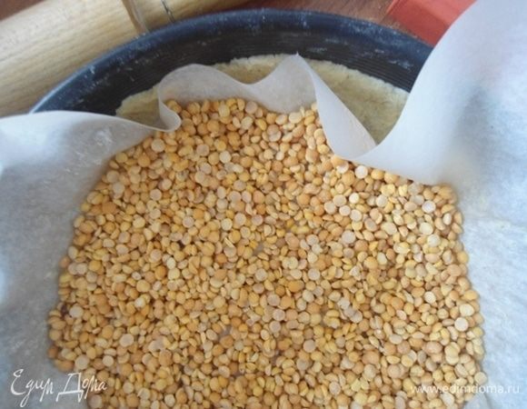 Перенести тесто в форму 26 мм, сверху накрыть бумагой и насыпать груз (фасоль или горох). Выпекать в разогретой до 200°С духовке 15 минут. Груз убрать.