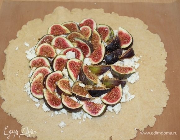 Затем тесто раскатать толщиной 5 мм, раскрошить сыр, сверху выложить дольки инжира, посыпать коричневым сахаром.