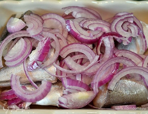 Лук нарезать полукольцами, переложить рыбу луком и уложить в форму.