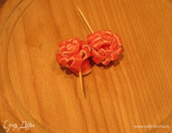 Пока замораживается мороженое, подготовим крабовую стружку как в рецепте «Хрустящие крабовые палочки». Но разнообразим декор «цветами» из крабовых палочек: срезаем цветную полосу, складываем вдвое и по сгибу делаем надрезы, сворачиваем, соединяем зубочисткой. Цветы сушим вместе со стружкой.