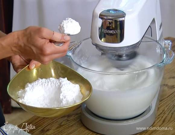 Продолжая взбивать, влить уксус и по одной ложке всыпать половину сахарной пудры.