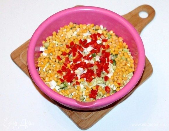 Выкладываем порезанные продукты в большую миску. Добавляем кукурузу без жидкости, сладкий перец (0,5 шт.), порезанный кубиками, и укроп (1/2 часть), перемешиваем.
