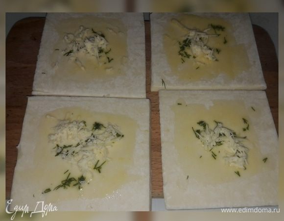 Слоеное дрожжевое тесто разморозить, разрезать на четыре части, добавить зелень, прованские травы или тимьян, смазать куриным желтком, сверху посыпать натертым сыром и отправить в духовку до готовности.