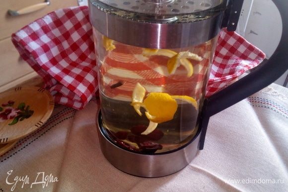 В заварный чайник положить ингредиенты: гвоздика, сушеные или свежие ягоды брусники, кожуру одного мандарина. Все залить кипятком, закрыть и настоять 10 минут.