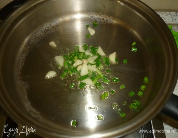 В большом сотейнике разогреть оливковое масло, выложить половину нарезанного зеленого лука, тушить до мягкости. Добавить нарезанный чеснок.