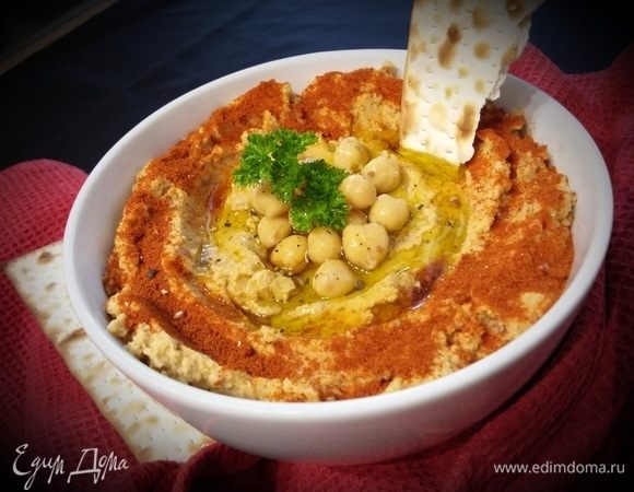 Готовый хумус переложить в пиалу, посыпать сладкой красной паприкой и полить оливковым маслом. По желанию добавить свежую зелень. 