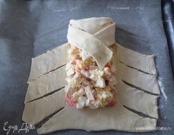 Подворачиваем верхний край на начинку, а затем накрываем начинку лентами теста, накладывая одну на другую. 