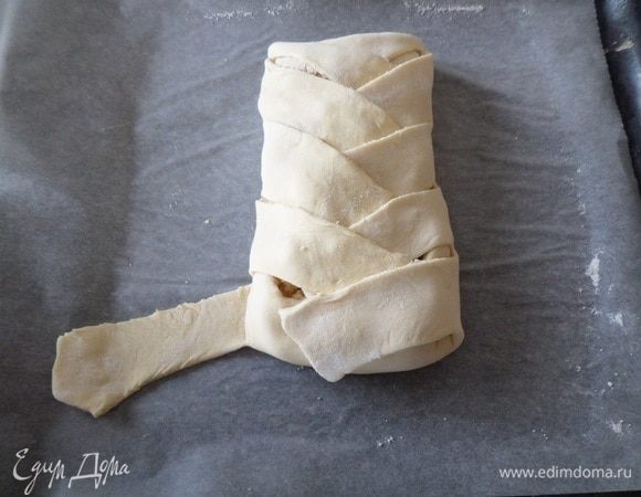 В конце укладываем нижний край на пирог, а затем накрываем последними двумя лентами теста. 