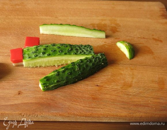 Теперь крабовый кубик будет меркой. По размеру кубика нарезаем огурец. Разрезаем пополам, высота среза должна быть не меньше высоты кубика. Срезаем с боков закругления и по ширине кубика нарезаем полоску.