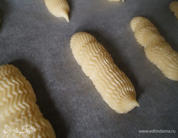 Наполнить кондитерский мешок с насадкой тестом и отсадить эклеры на противень застеленный бумагой для выпечки. Поставить противень в разогретую до 180°С духовку и выпекать эклеры не открывая дверку (иначе они опадут). Время выпечки будет зависеть от конкретной духовке. В итоге готовые эклеры должны получиться красивого золотого цвета сверху и пустыми, сухими внутри. 